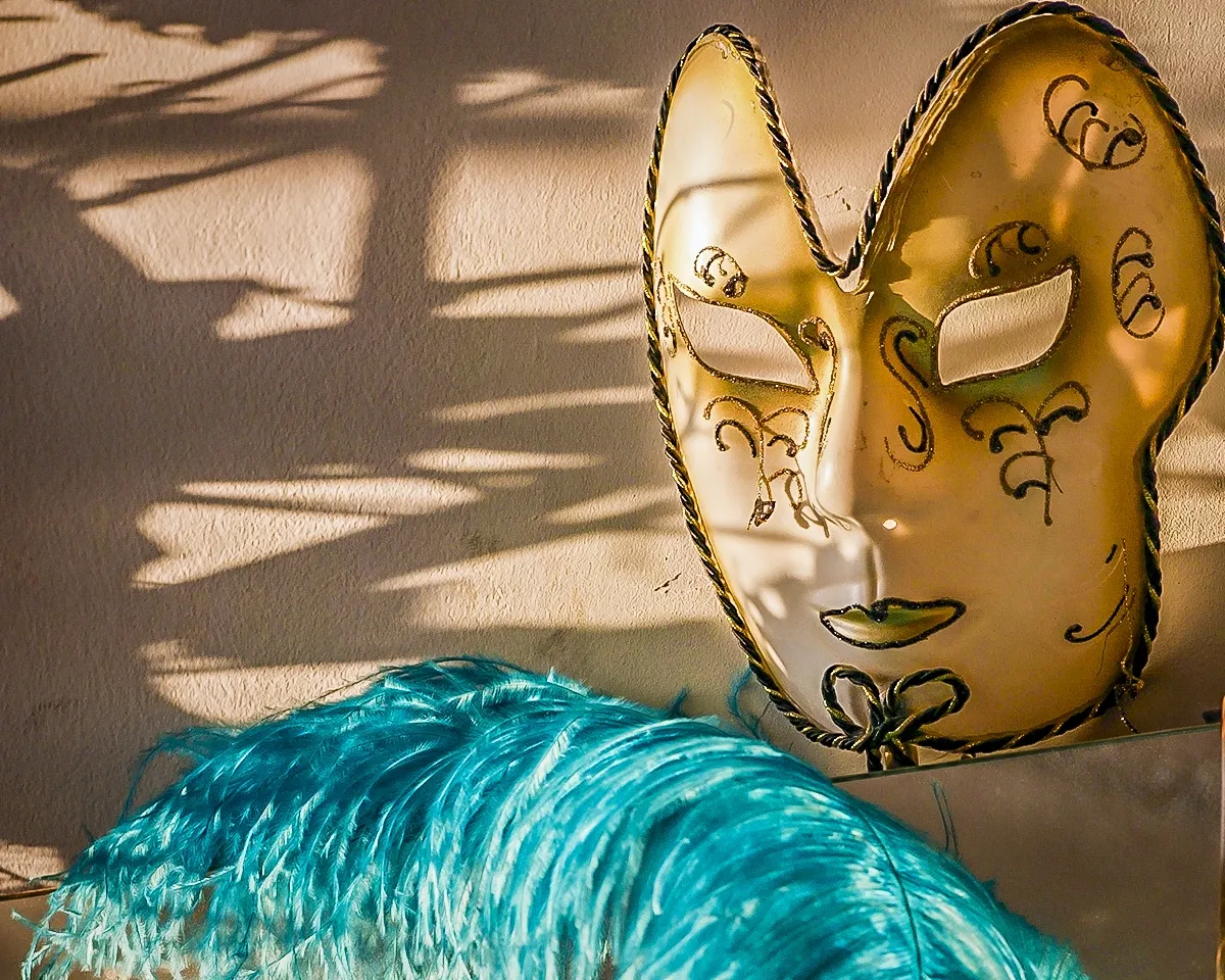Gold carnival mask beside a bright blue feather boa